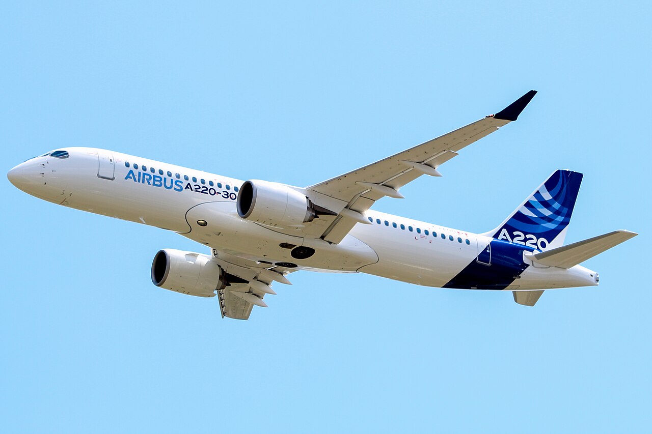 An Airbus A220-300 in flight against a blue sky